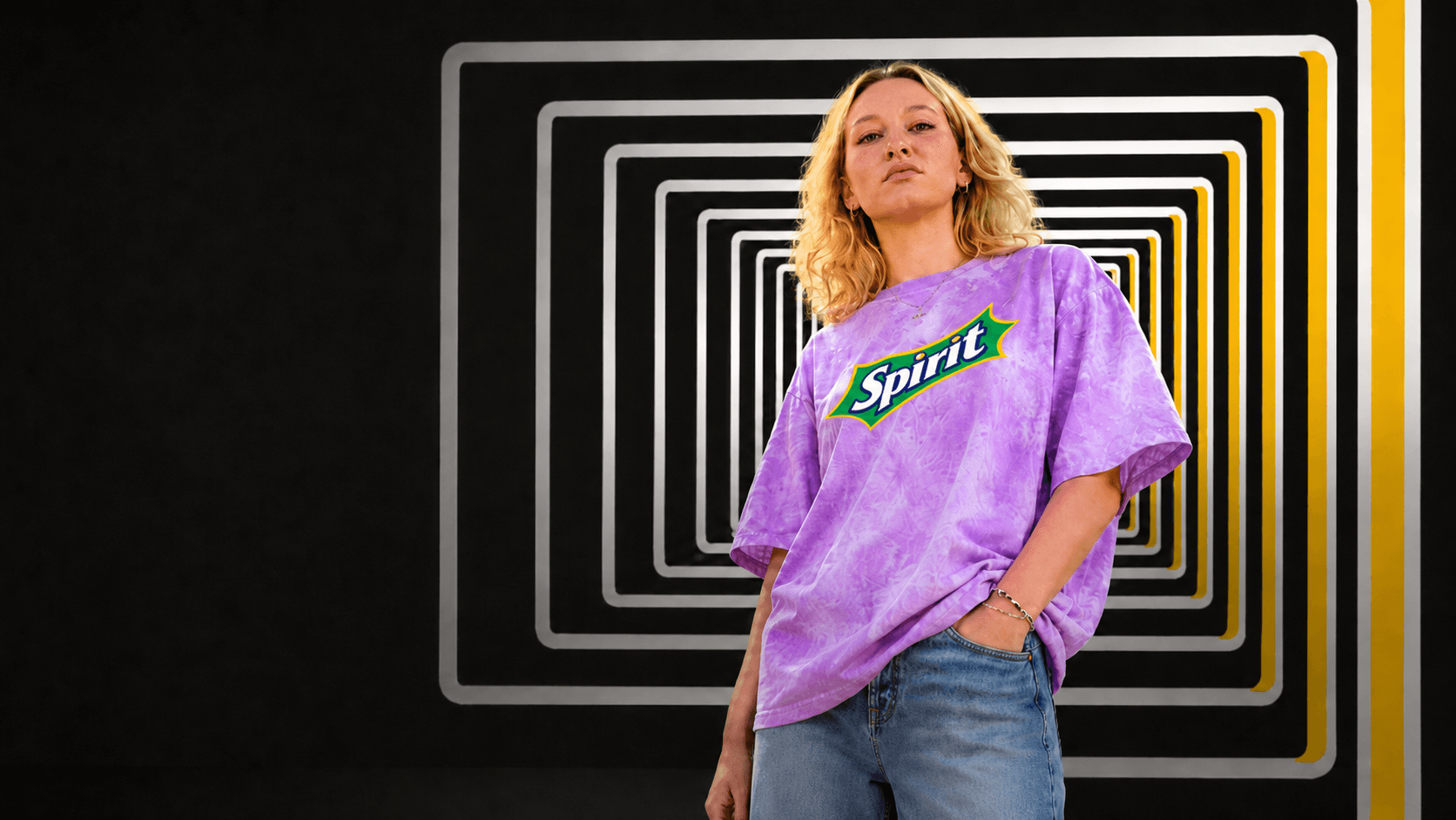 Model im violetten Spirit T-Shirt vor geometrischer Perception-Lab-Kulisse